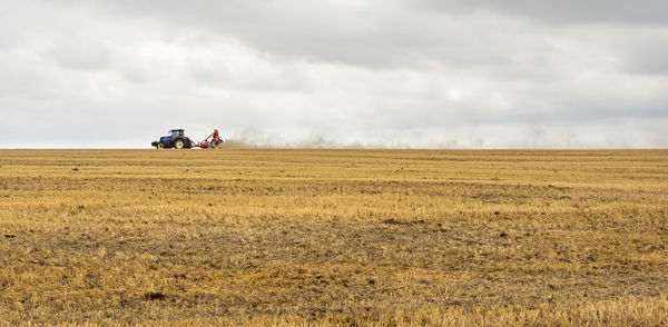 Stormy farmland scenery showing a tractor on a stubble field in hohenlohe