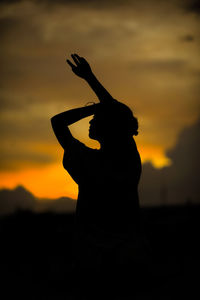 Silhouette woman standing against orange sky
