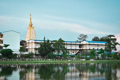 Buildings by lake against sky