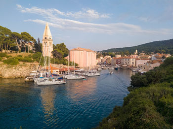 Sailboats in city by buildings against sky