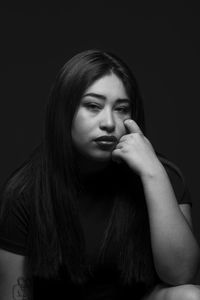 Portrait of beautiful young woman against black background