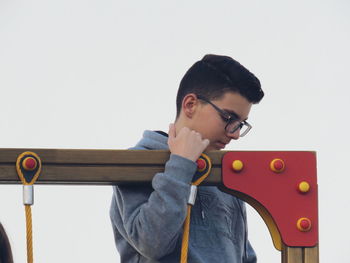 Boy standing by play equipment against white background