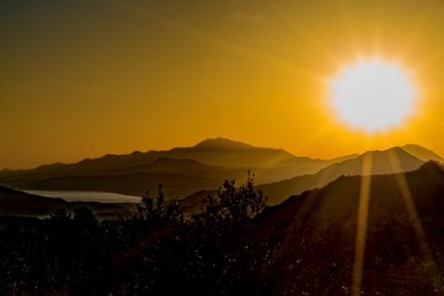 Scenic view of silhouette mountains against orange sky