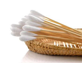 Close-up of cotton swabs in container against white background