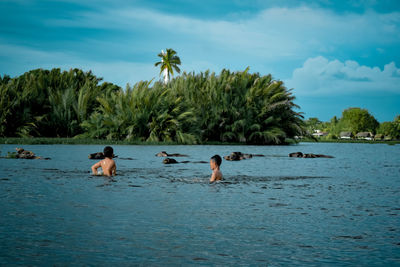 People swimming in sea against sky