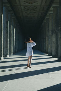 Rear view of woman standing at colonnade