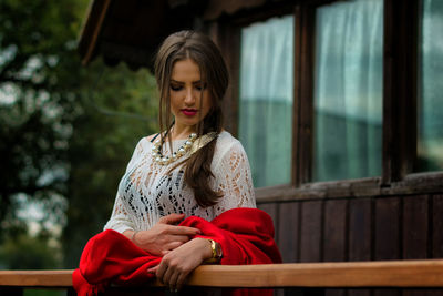 Beautiful young woman with red shawl standing in balcony