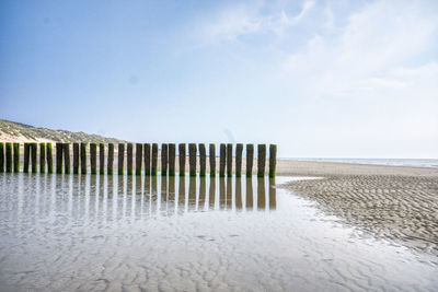 Wooden posts on beach against sky