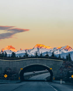 Arch bridge and snowcapped mountains against sky during sunset
