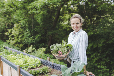 Portrait of smiling young man standing against plants