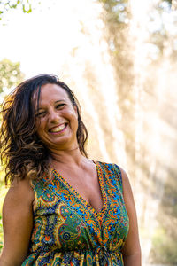 Portrait of beautiful middle aged woman in front of a fountain in a park at sunset