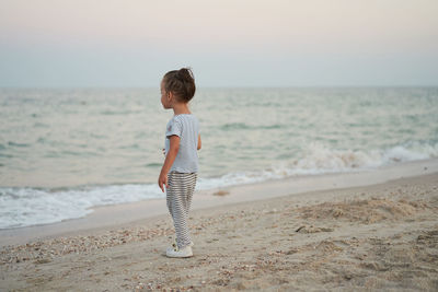 Full length of boy on beach against sky during sunset