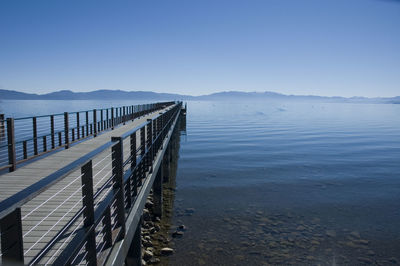 Pier over sea against clear blue sky