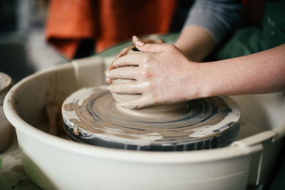 Woman hands moulding ceramic piece on potters wheel