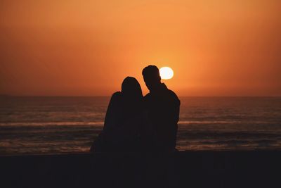 Silhouette couple against sea during sunset