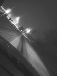 Illuminated street against sky at night