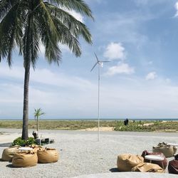 Rear view of woman relaxing at beach against sky