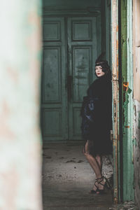 Woman standing against door of building