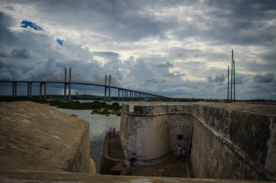 Bridge over sea against cloudy sky