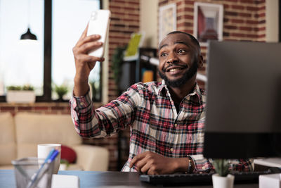 Portrait of young woman using mobile phone while standing in cafe