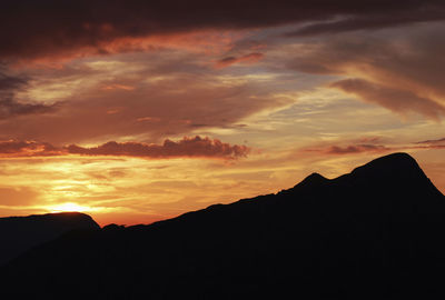 Scenic view of silhouette mountains against orange sky