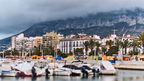 Sailboats in city by buildings against sky