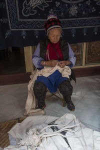 Full length of girl sitting on bed at home