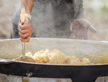 Midsection of man preparing food in utensil