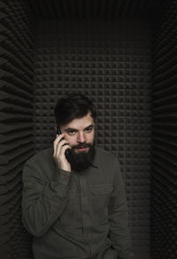 Portrait of young man standing against wall