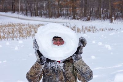Teenage boy playing with snow on field during winter