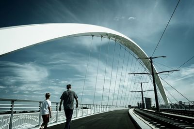 Rear view of people on bridge against sky