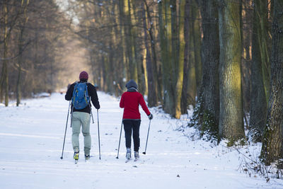 Rear view of girls walking in snow covered forest