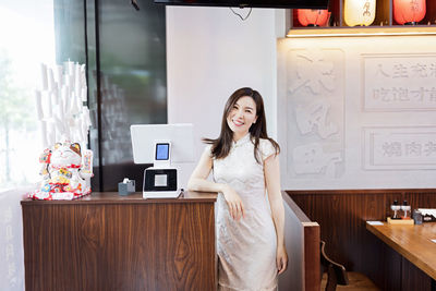 Portrait of smiling young woman standing at home