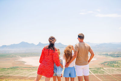 Rear view of women standing on landscape against sky