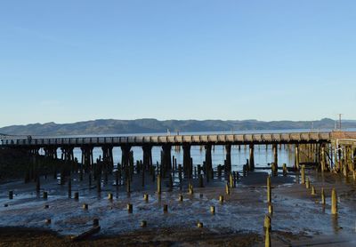 Wooden posts in lake against clear blue sky