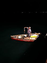 Rear view of man sitting on illuminated boat at night