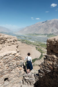 Rear view of man on rock against sky