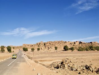 Scenic view of desert road against blue sky
