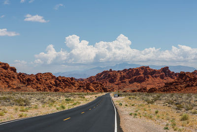 Road by mountains against sky