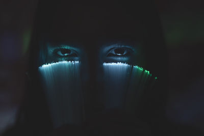 Close-up portrait of young woman in dark room