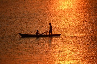 Silhouette people on boat against sea during sunset