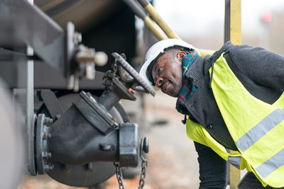 African american mechanic wearing safety equipment checking and inspecting gear train