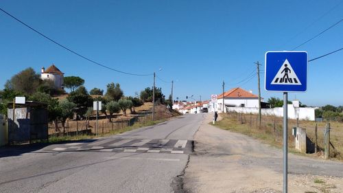 Road by trees against clear blue sky