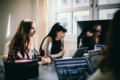 Colleagues sitting at table with laptops in office