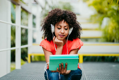 Young woman looking away while sitting on mobile phone