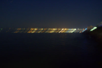 Illuminated cityscape against sky at night