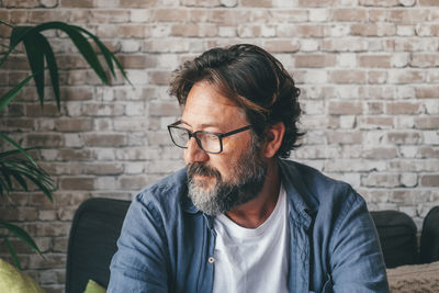 Side view of man looking away against wall