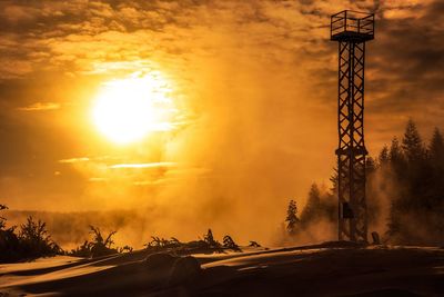 Silhouette built structure against orange sky during sunset