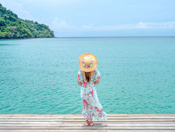 Boy standing in sea against sky