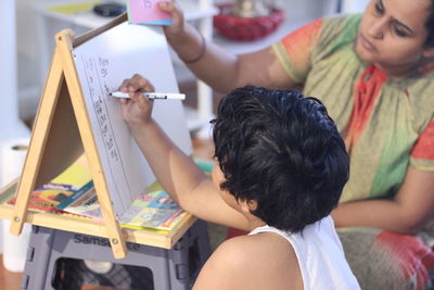 Rear view of girl writing on board